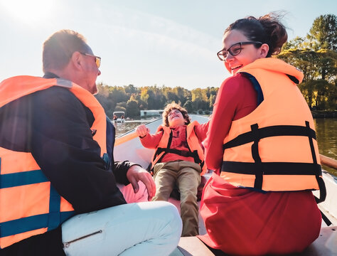 Cheerful Father, Little Son And Teenage Daughter Sitting On Boat In Life Vests On Summer Day. Family Walks At The Boat Station, Selective Focus