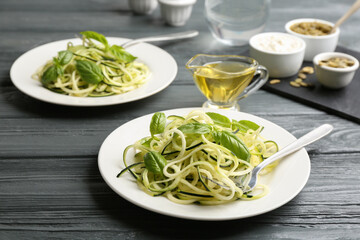 Delicious zucchini pasta with basil served on grey wooden table