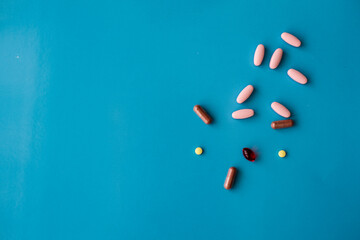 Different colors medical pills on blue background with copy space. 
