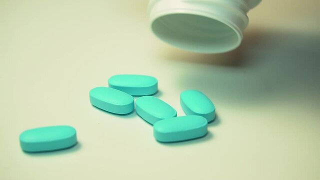 Sideways pan on oxycodone, the generic name for a range of opoid pain killing tablets. Prescription bottle for Oxycodone tablets and pills on wooden table with USA flag in background