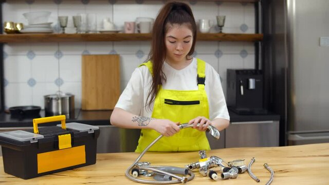Portrait of woman plumber assembling showerhead at kitchen table