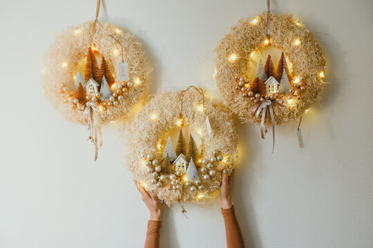 Three Handmade Christmas Wreath with Lights in Woman Hands for Winter holidays tradition, Lght garland, Natural and Ecofriendly Materials