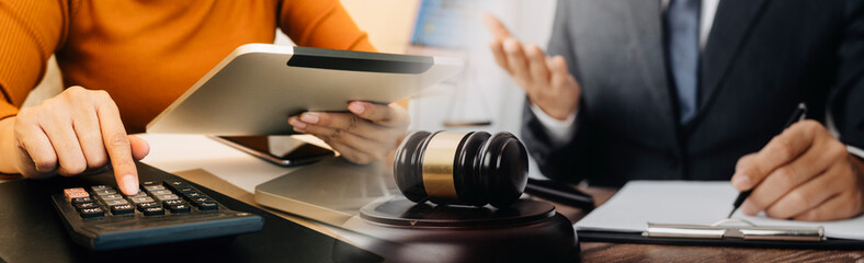 Justice and law concept.Male judge in a courtroom with the gavel, working with, computer and docking keyboard, eyeglasses, on table in morning light