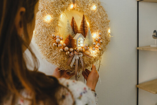 Handmade Christmas Wreath with Lights in Woman Hands for Winter holidays tradition, Lght garland, Natural and Ecofriendly Materials