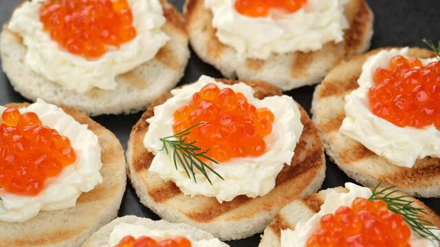 toast with red caviar and soft cheese close up rotation. Christmas party food