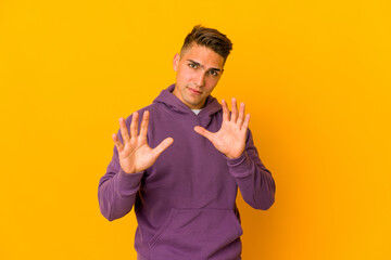 Young handsome caucasian man isolated rejecting someone showing a gesture of disgust.