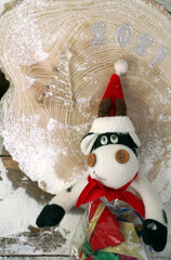 toy bull in a santa hat with a bag of gifts on a wooden background