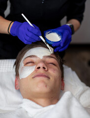 Teenager with dark hair is undergoing a procedure to treat problem skin in a beauty salon. Facial Skin Care. cleansing procedure