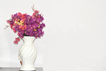 Flowers in a vase on a white background wall