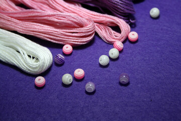 Beads and sewing threads for embroidery on a felt background.