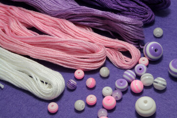 Beads and sewing threads for embroidery on a felt background.