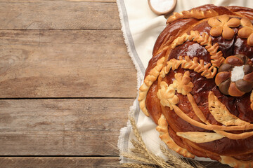 Korovai with wheat spikes on wooden table, space for text. Ukrainian bread and salt welcoming tradition