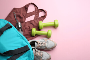 Flat lay composition with sportswear, gym bag and dumbbells on pink background, space for text