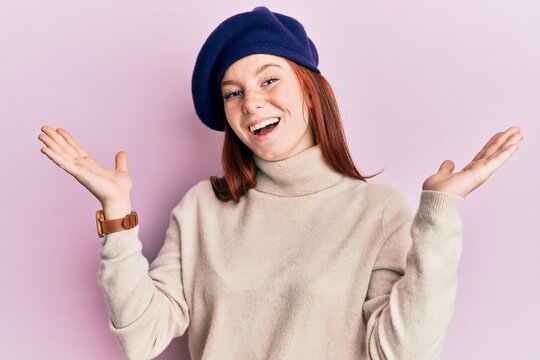 Young red head girl wearing french look with beret celebrating victory with happy smile and winner expression with raised hands