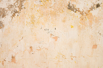 Grunge background of cracked peeling walls with peeled putty in beige tones