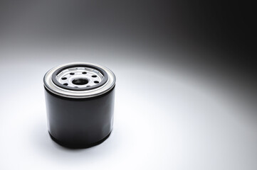 Black new oil filter in contrasting light on a black and white background. Wide angle