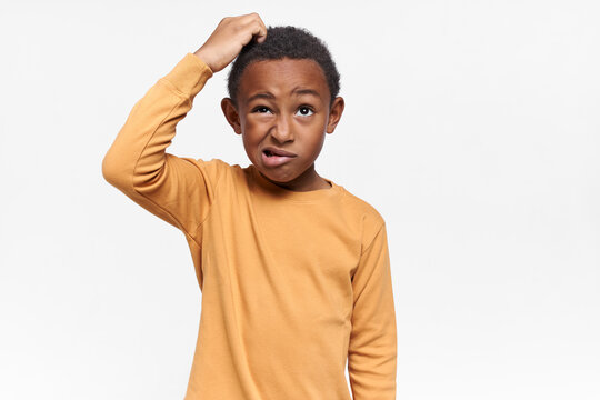 Isolated image of perplexed frustrated African American schoolboy grimacing and looking up, scratching his head, having confused facial expression, forgot something important. Body language