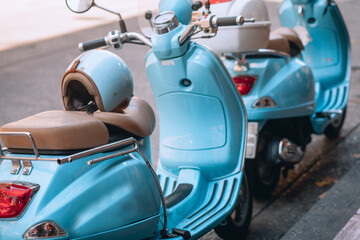 Small pretty blue motorbikes with helmets are parked near the roadway