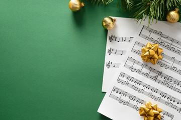 Blank for Christmas Carols and sings decorated golden balls on green background. View from above.