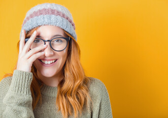 Joke. Happy woman looking through his fingers, isolated on yellow background. Playful trendy girl