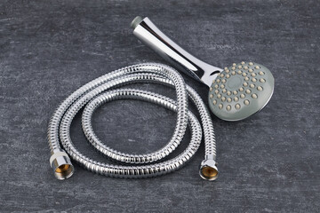 Showerhead and flexible connection hose close-up on grey shabby background