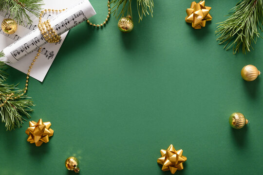 Music frame for Christmas Carols and sings decorated golden balls on green background. View from above. Space for text.