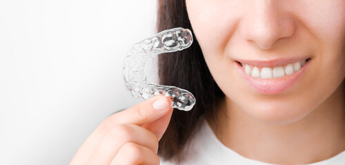 Close up woman holding a transparent removable braces for perfect smile. Orthodontic aligners for straightening and whitening teeth. © vladim_ka