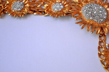Frame of golden necklaces with golden flowers and with gems on white background