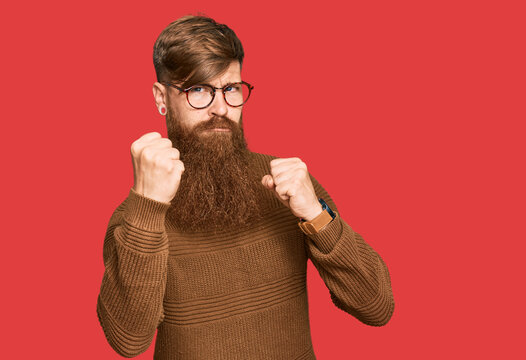 Young irish redhead man wearing casual clothes and glasses ready to fight with fist defense gesture, angry and upset face, afraid of problem