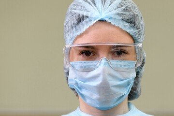 Female doctor in protective glasses and medical face mask, close-up.