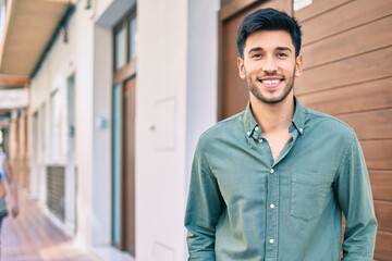 Young latin man smiling happy walking at the city.