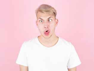 Young attractive guy makes a grimace with eyes crossed and his tongue sticking out.