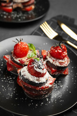 Baked eggplant with tomatoes, cheese and basil on black table, closeup