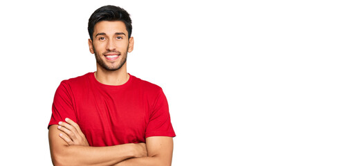 Young handsome man wearing casual red tshirt happy face smiling with crossed arms looking at the...