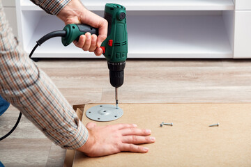 Furniture assembly process, master collects table furniture using drill tool instrument. Moving, home improvement, furniture repair renovation