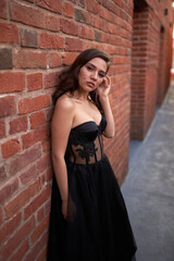 Full-length portrait of an elegant brunette woman with long hair in a black long evening dress.