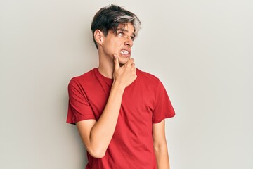 Young hispanic man wearing casual clothes thinking worried about a question, concerned and nervous with hand on chin