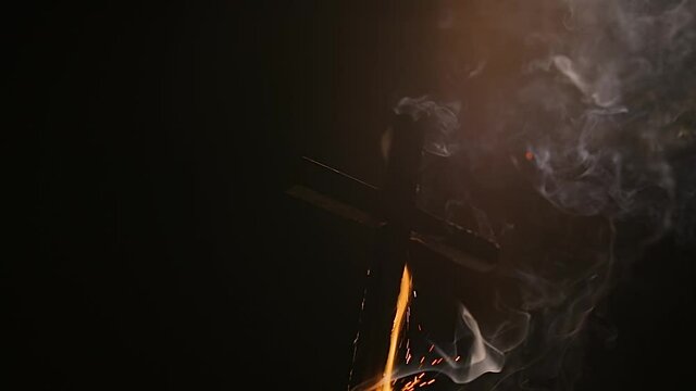 Burning cross falling down with smoke in the darkness of night