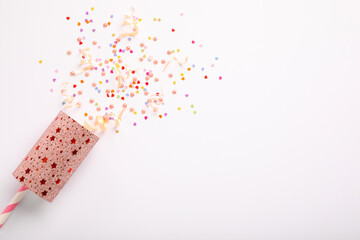 Colorful confetti and streamers with party cracker on white background, top view. Space for text