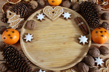 Christmas background with gingerbread, nuts, cinnamon sticks, pine cones and mandarins