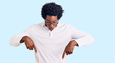 Handsome african american man with afro hair wearing casual clothes and glasses pointing down with...
