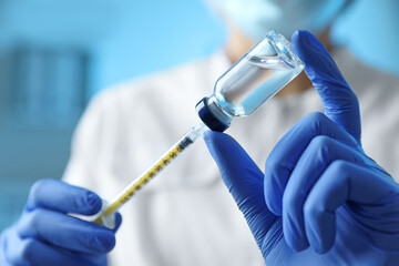 Doctor filling syringe with medication in clinic, closeup. Vaccination and immunization