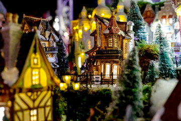 Toy house European Chocolate Shop on christmas eve in Christmas trees in toy city with glowing windows. Winter Christmas Eve scene with traditional miniature village houses. Vintage toy city