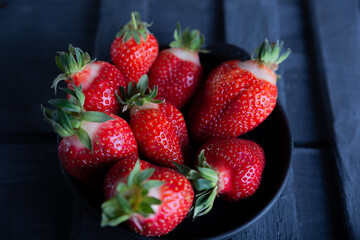 Fresh ripe strawberries on a black wooden background