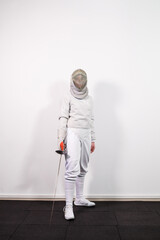 Girl in a fencing costume with a sword in hand isolated on white studio background. Young girls...