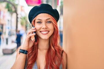 Young redhead girl wearing french style talking on the smartphone at the city.