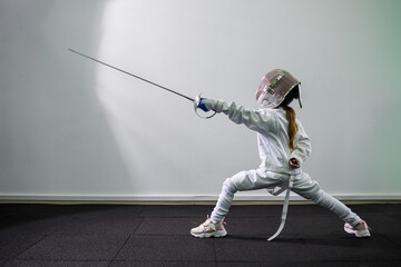 Children lunge on swords. A child in a class at a fencing school