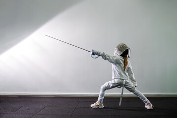 Children lunge on swords. A child in a class at a fencing school