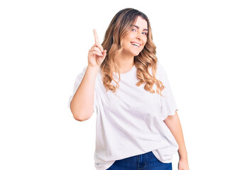 Fototapeta premium Young caucasian woman wearing casual clothes pointing finger up with successful idea. exited and happy. number one.