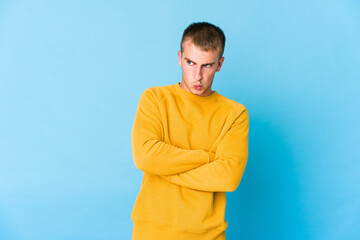 Young caucasian handsome man frowning face in displeasure, keeps arms folded.